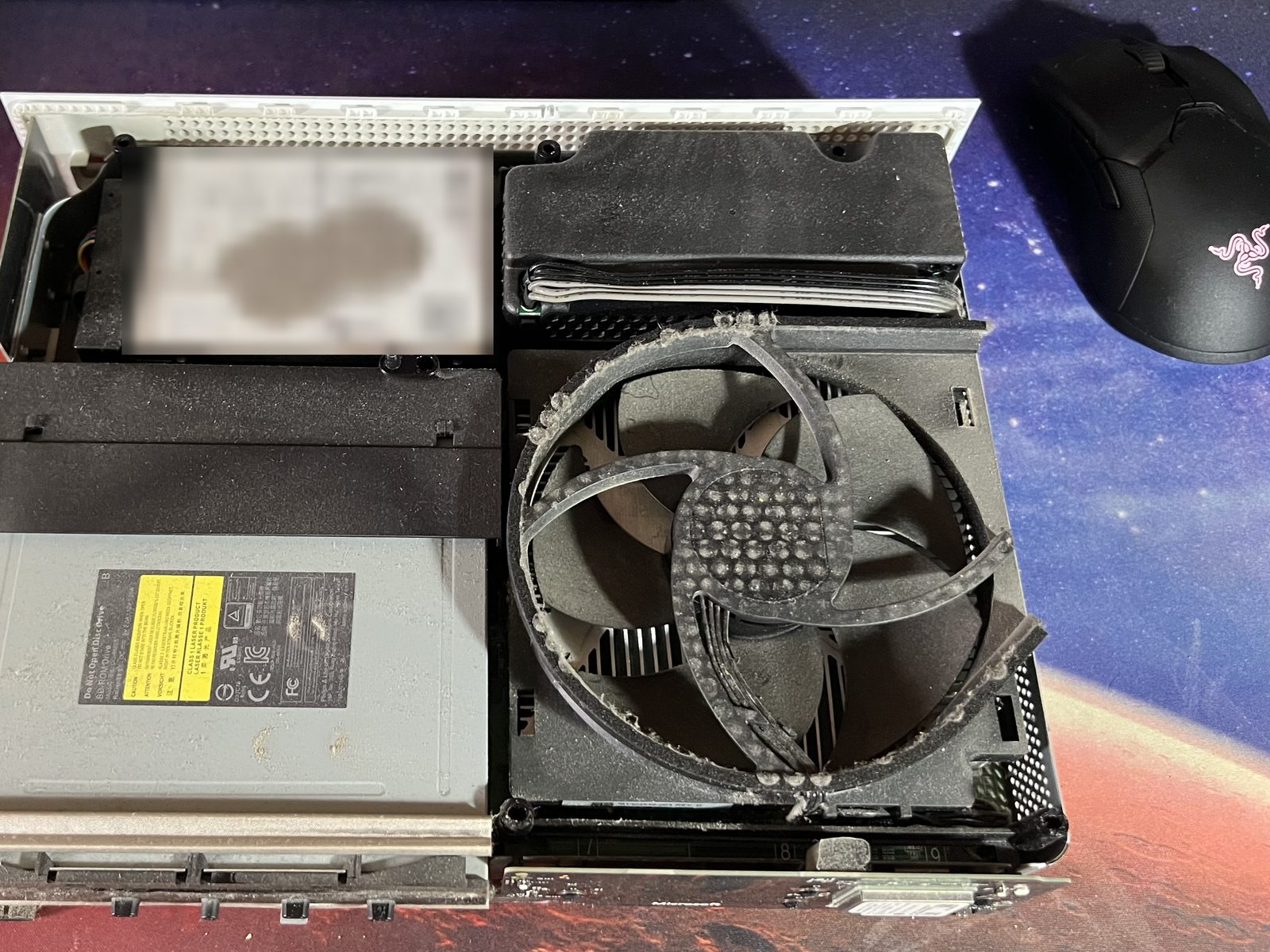 L'interno della Xbox One S prima della pulizia, con la ventola coperta di polvere
